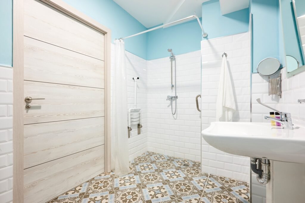 Salle de bain PMR à Amiens avec douche à l’italienne, barre d’appui et carrelage métro blanc.