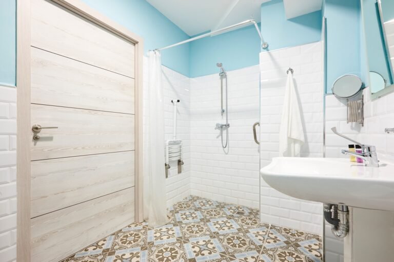 Salle de bain PMR à Amiens avec douche à l’italienne, barre d’appui et carrelage métro blanc.