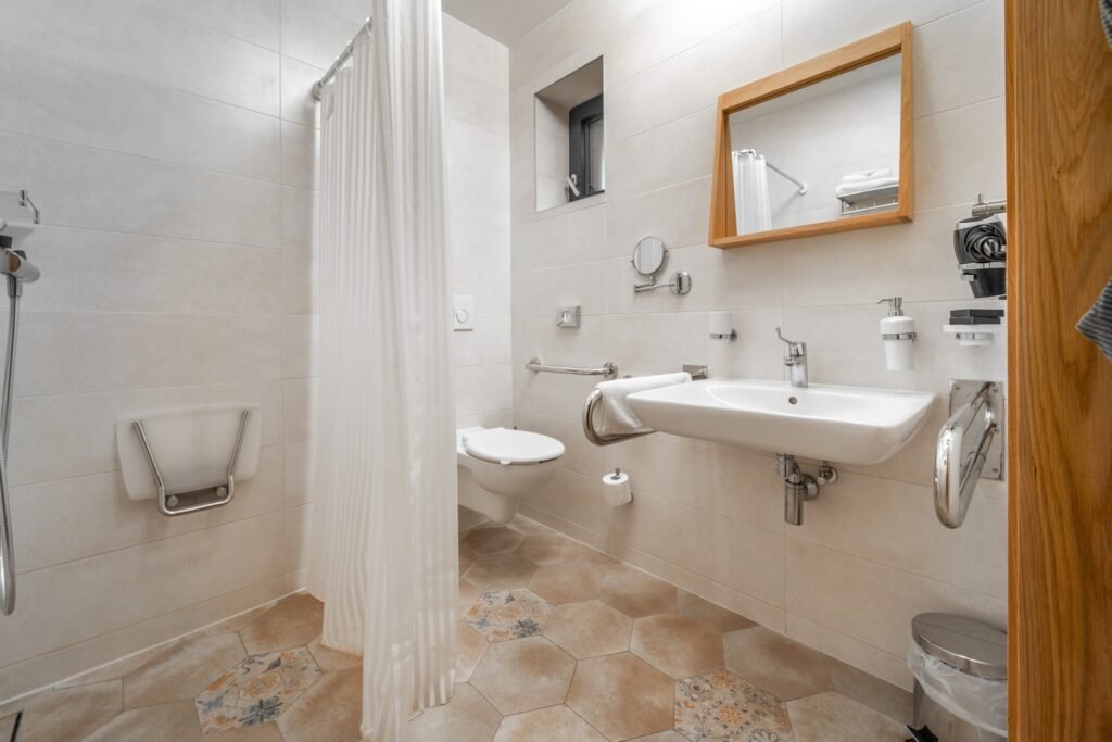 Salle de bain PMR à Amiens avec douche à l’italienne, barre d’appui et carrelage métro blanc.
