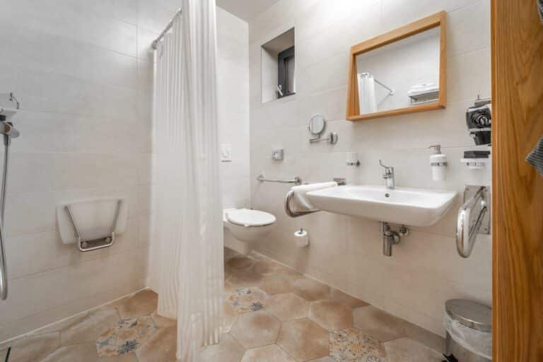 Salle de bain PMR à Amiens avec douche à l’italienne, barre d’appui et carrelage métro blanc.