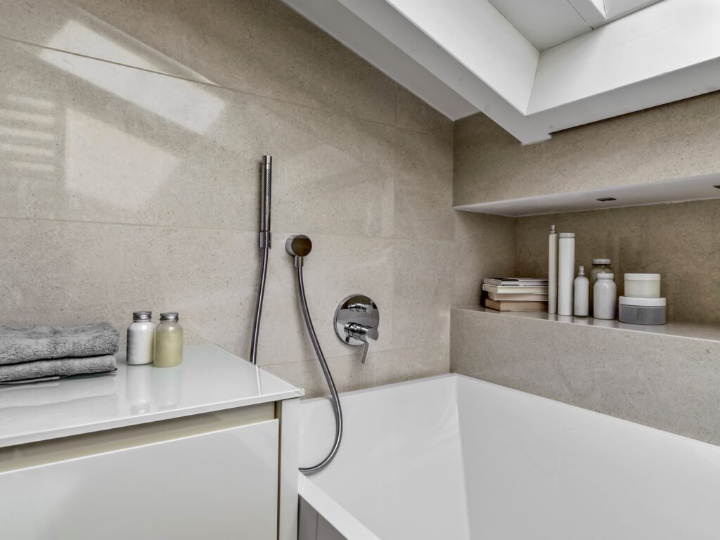 Détail d’une baignoire encastrée à Amiens avec carrelage effet pierre et robinet mural.