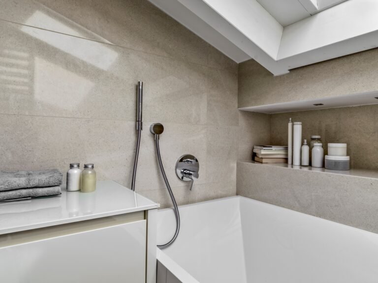 Détail d’une baignoire encastrée à Amiens avec carrelage effet pierre et robinet mural.