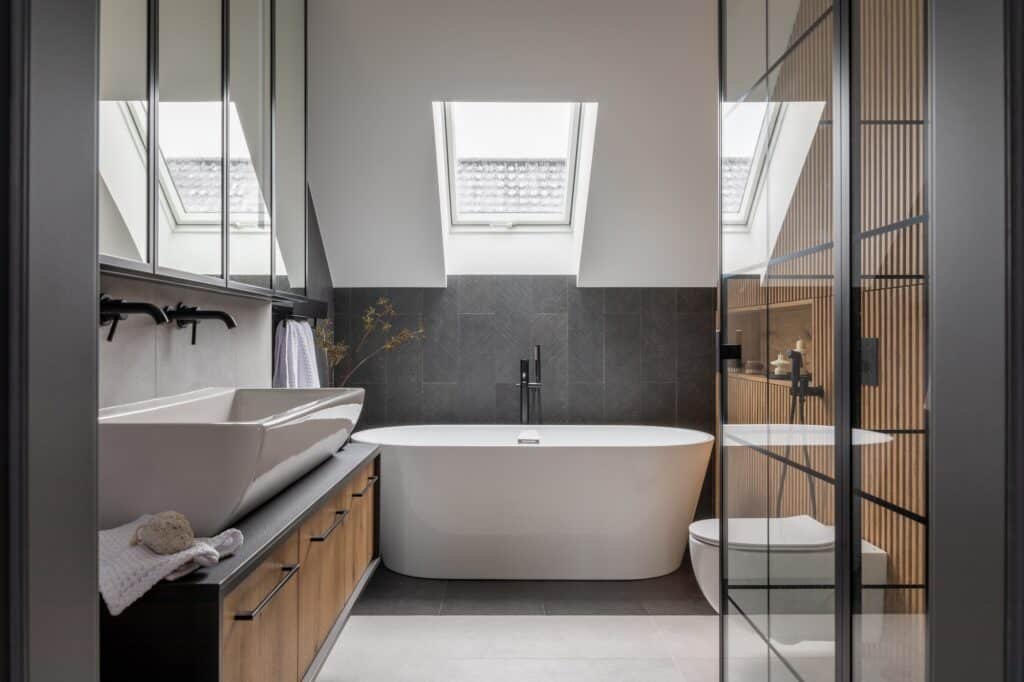 Salle de bain moderne à Amiens avec baignoire îlot sous puits de lumière et meuble en bois.