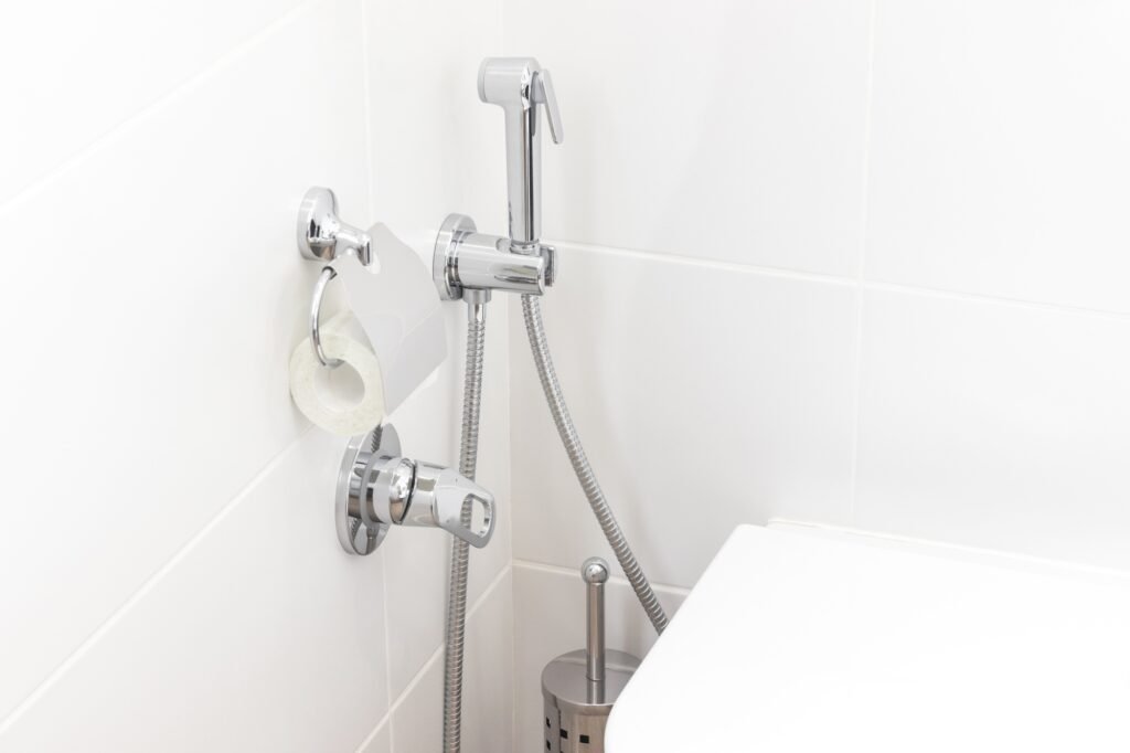 Mitigeur et douchette murale posés à côté d’un WC suspendu dans une salle de bain à Amiens.