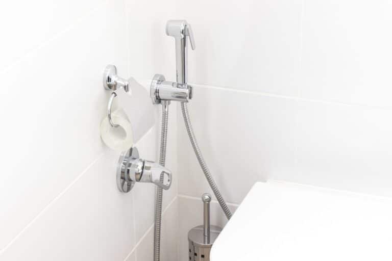Mitigeur et douchette murale posés à côté d’un WC suspendu dans une salle de bain à Amiens.