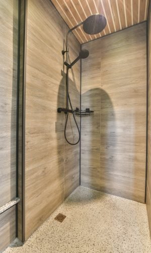 Douche à l’italienne à Amiens avec carrelage de salle de bain en bois et robinetterie noire.